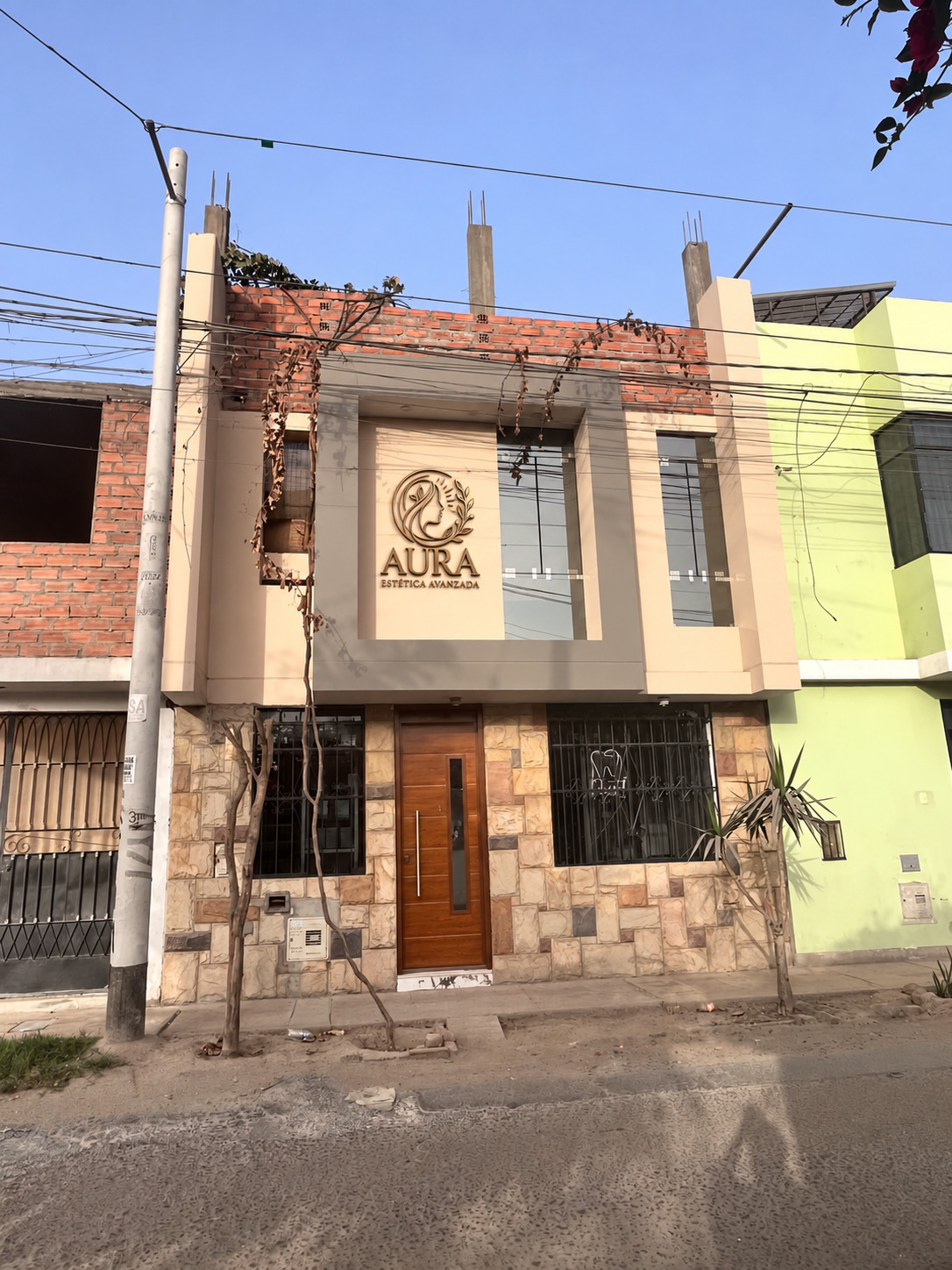 Fachada de Aura Estética Avanzada en Ica, con su logotipo dorado y puerta de madera